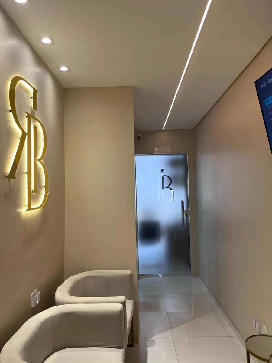 Corredor da clínica com o monograma RB iluminado na parede